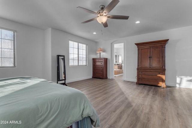 bedroom with connected bathroom, light hardwood / wood-style floors, and ceiling fan