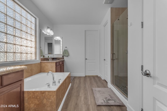 bathroom with vanity, hardwood / wood-style flooring, and plus walk in shower