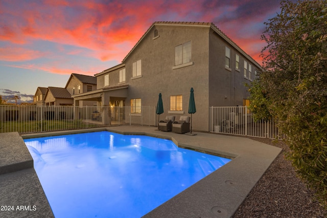 pool at dusk featuring a patio