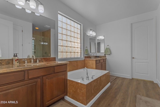 bathroom featuring wood-type flooring, separate shower and tub, and vanity