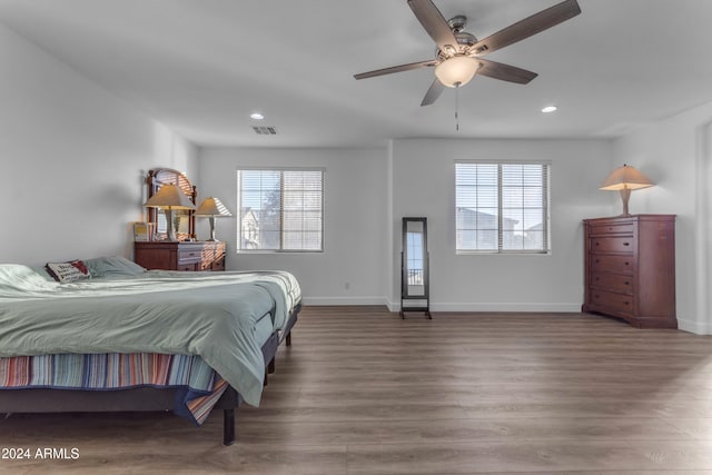 bedroom featuring hardwood / wood-style flooring, ceiling fan, and multiple windows