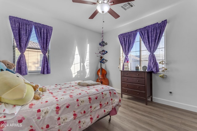 bedroom featuring ceiling fan, wood-type flooring, and multiple windows