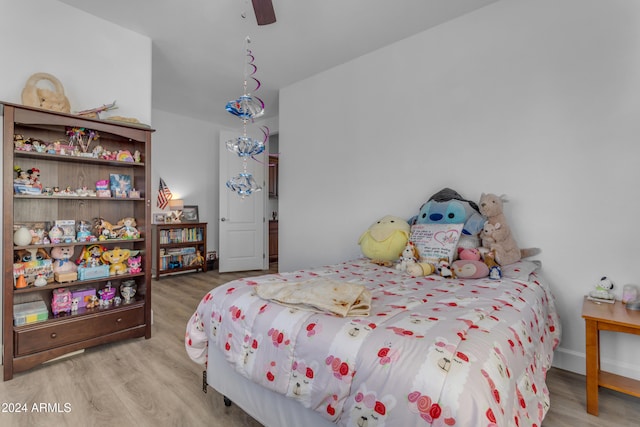 bedroom featuring ceiling fan with notable chandelier and light wood-type flooring