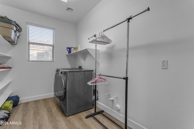 laundry room with washing machine and clothes dryer and light hardwood / wood-style floors