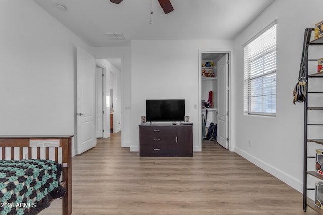 bedroom featuring ceiling fan, a walk in closet, and light wood-type flooring