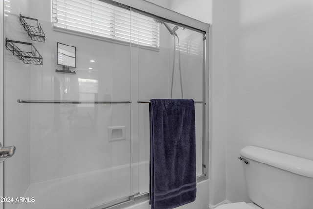 bathroom featuring shower / bath combination with glass door and toilet