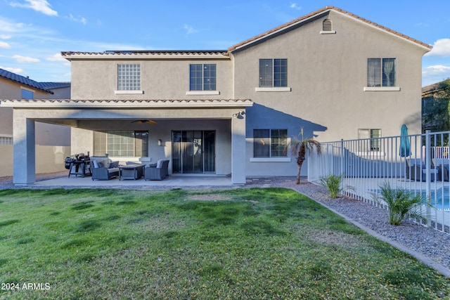 rear view of house with an outdoor living space, a patio area, ceiling fan, and a lawn