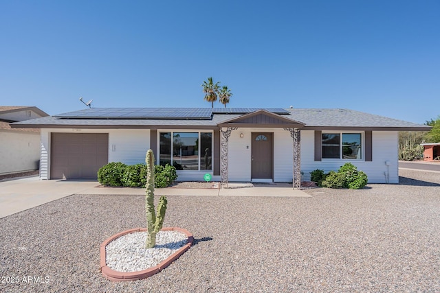 single story home featuring concrete driveway, an attached garage, and roof mounted solar panels