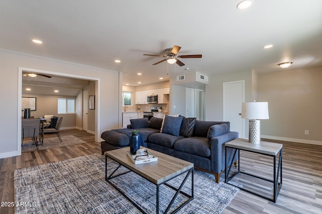 living room with recessed lighting, visible vents, light wood finished floors, and baseboards