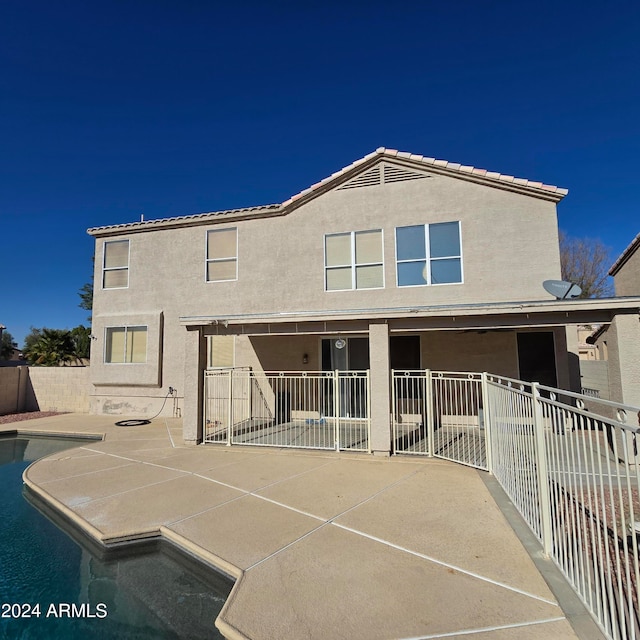 rear view of property featuring a patio area and a fenced in pool