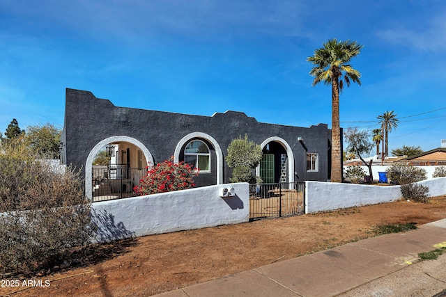 view of front of house featuring a fenced front yard, a gate, and stucco siding