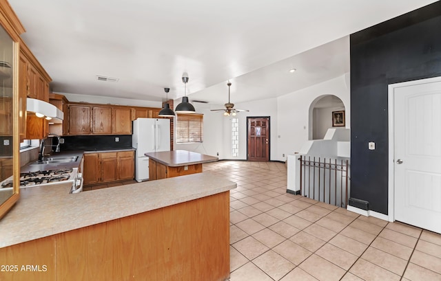 kitchen with visible vents, freestanding refrigerator, a peninsula, light countertops, and a sink