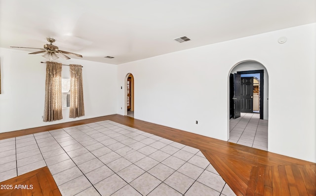 spare room featuring arched walkways, visible vents, ceiling fan, and light tile patterned floors