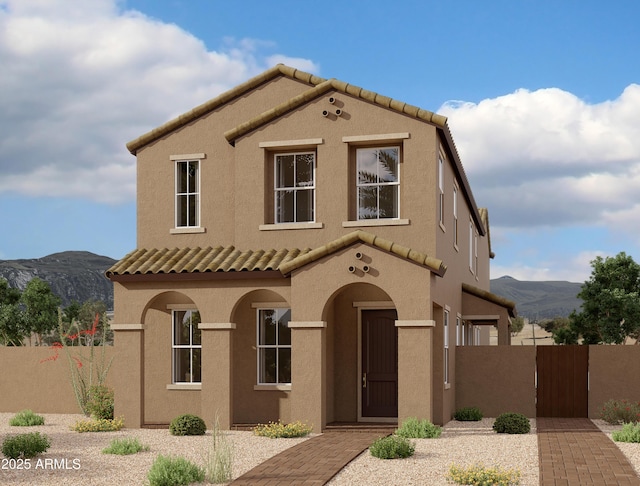 mediterranean / spanish-style house featuring a tile roof, a gate, fence, a mountain view, and stucco siding