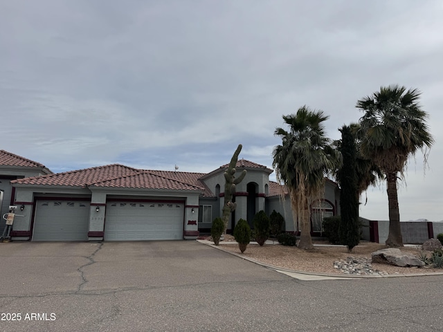 view of front facade featuring a garage, driveway, a tile roof, and stucco siding