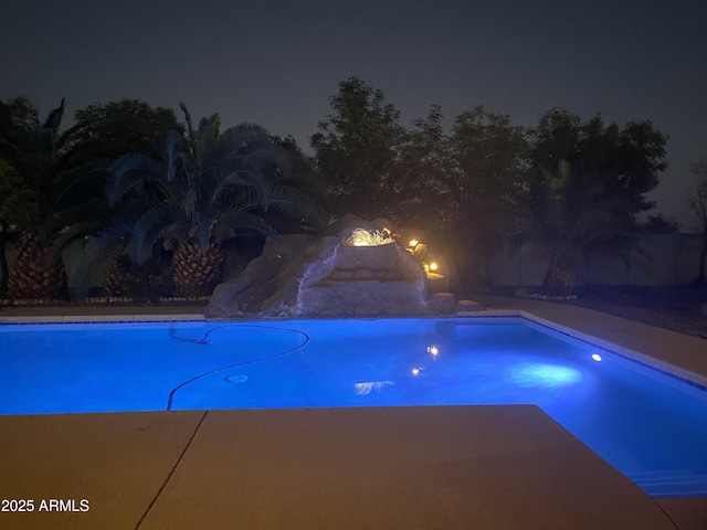 pool at night featuring a water slide and an outdoor pool