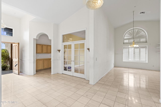 tiled empty room featuring a notable chandelier and high vaulted ceiling