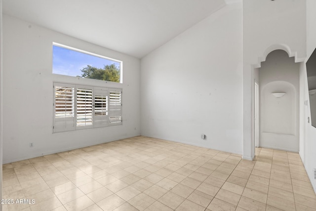 tiled spare room with high vaulted ceiling