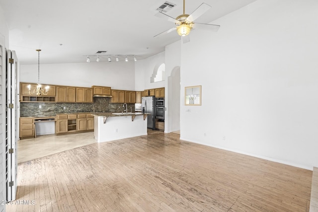 kitchen featuring high vaulted ceiling, tasteful backsplash, a breakfast bar area, hanging light fixtures, and stainless steel appliances