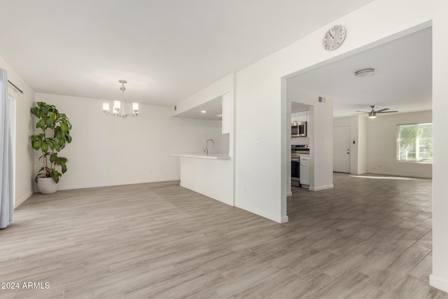 unfurnished living room featuring sink, ceiling fan with notable chandelier, and light wood-type flooring