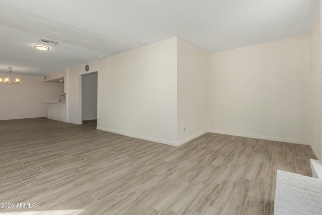 empty room with light hardwood / wood-style floors and a notable chandelier