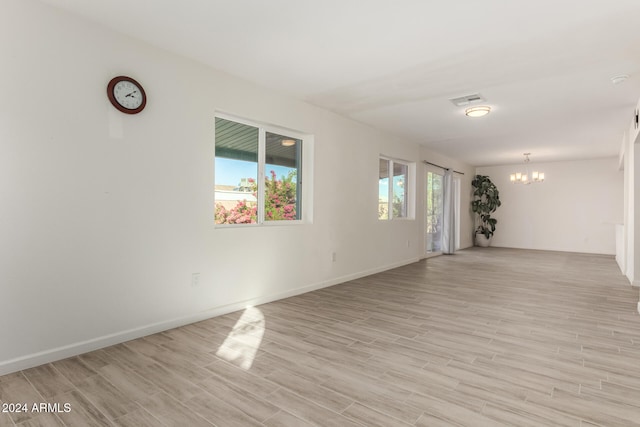 unfurnished room featuring light hardwood / wood-style flooring and a chandelier