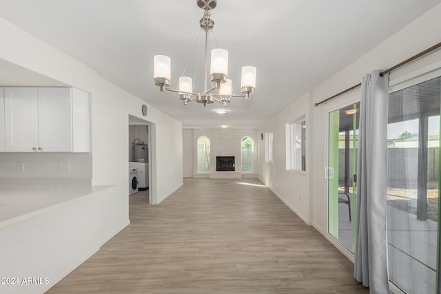 hall featuring light hardwood / wood-style floors, a chandelier, and washer / dryer