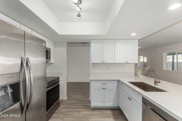 kitchen with sink, appliances with stainless steel finishes, light hardwood / wood-style flooring, and white cabinetry