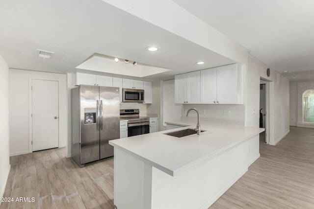 kitchen with sink, appliances with stainless steel finishes, kitchen peninsula, and white cabinets