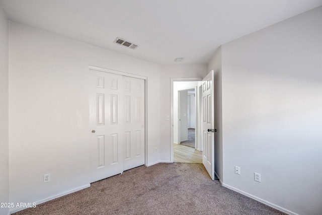 unfurnished bedroom with light colored carpet and a closet