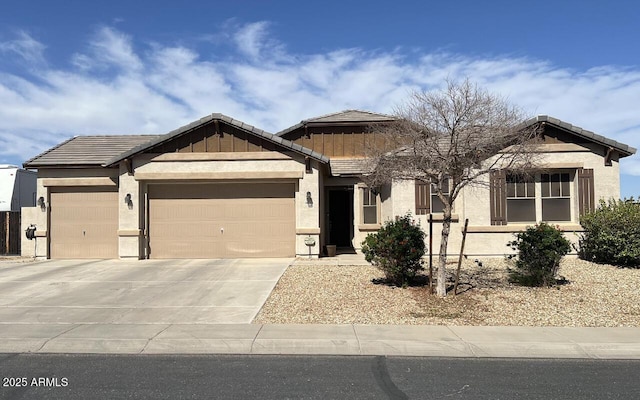 view of front of house with a tiled roof, a garage, driveway, and stucco siding