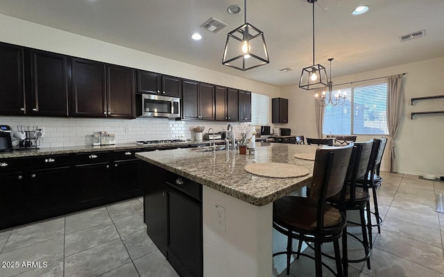 kitchen with a sink, stainless steel appliances, visible vents, and decorative backsplash