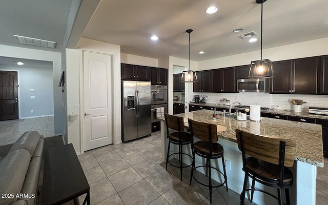 kitchen with a breakfast bar area, tasteful backsplash, visible vents, and stainless steel appliances