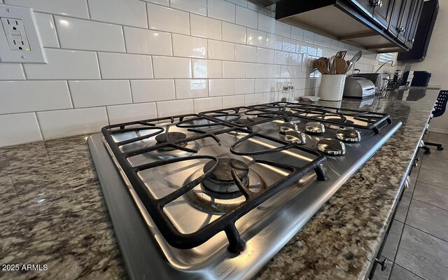 interior details featuring tasteful backsplash, dark stone counters, and stainless steel gas stovetop