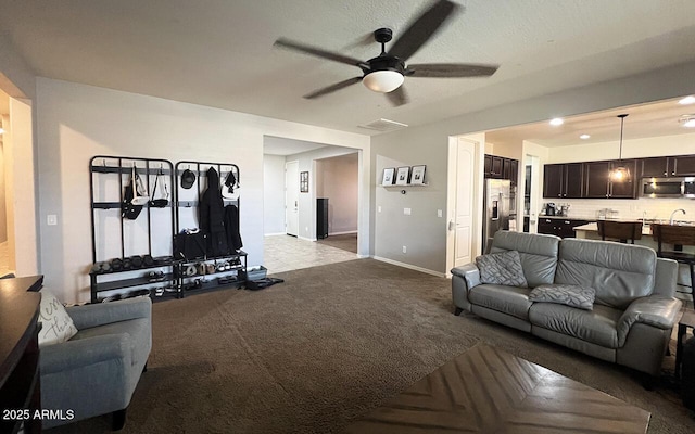 living room featuring baseboards, light carpet, and a ceiling fan