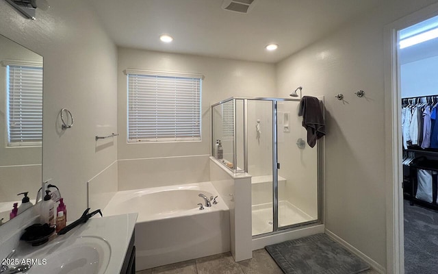 bathroom with a walk in closet, a stall shower, tile patterned flooring, a bath, and vanity