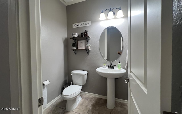 bathroom with tile patterned flooring, toilet, baseboards, and a sink