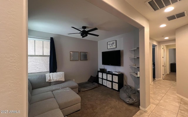 living area featuring light tile patterned flooring, visible vents, light colored carpet, and a ceiling fan