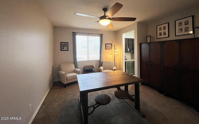 office area with beverage cooler, a ceiling fan, baseboards, and light carpet