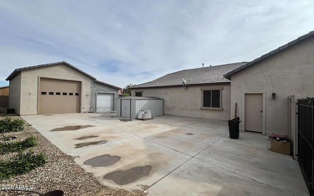 view of side of property with stucco siding, a detached garage, and an outdoor structure