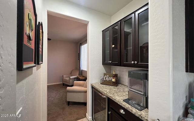 kitchen with light stone counters, carpet, decorative backsplash, wine cooler, and glass insert cabinets