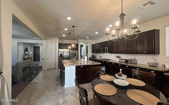 kitchen with tasteful backsplash, visible vents, dark brown cabinets, a kitchen bar, and appliances with stainless steel finishes