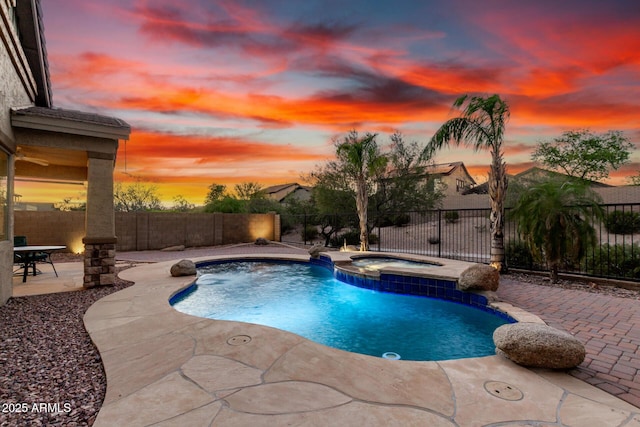 12702 W Dove Wing Way, Peoria, AZ 85383 - pool at dusk with a fenced backyard, a patio, and a pool with connected hot tub