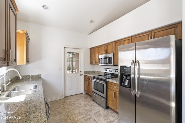 kitchen with sink, light tile patterned floors, light stone countertops, and stainless steel appliances