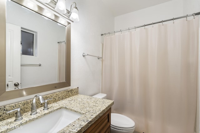 bathroom featuring toilet, vanity, and curtained shower