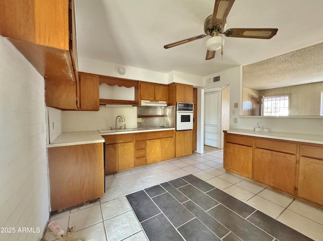 kitchen with sink, ceiling fan, white oven, a textured ceiling, and light tile patterned flooring