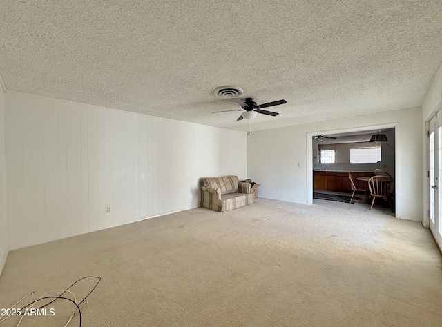 interior space featuring ceiling fan, a textured ceiling, and wood walls