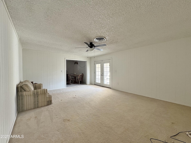 interior space with french doors, ceiling fan, light carpet, and a textured ceiling