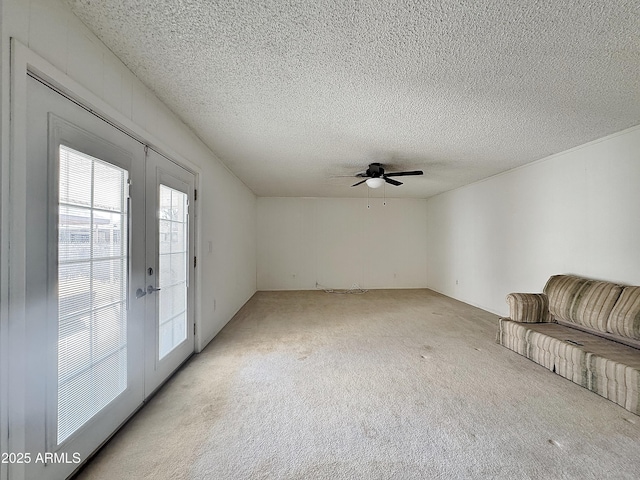 unfurnished living room featuring french doors, light carpet, and a textured ceiling