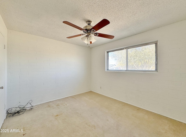 carpeted empty room with ceiling fan, brick wall, and a textured ceiling